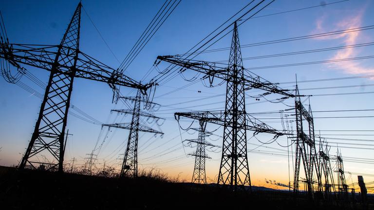 Kurz vor Sonnenaufgang stehen Masten auf einem Feld.