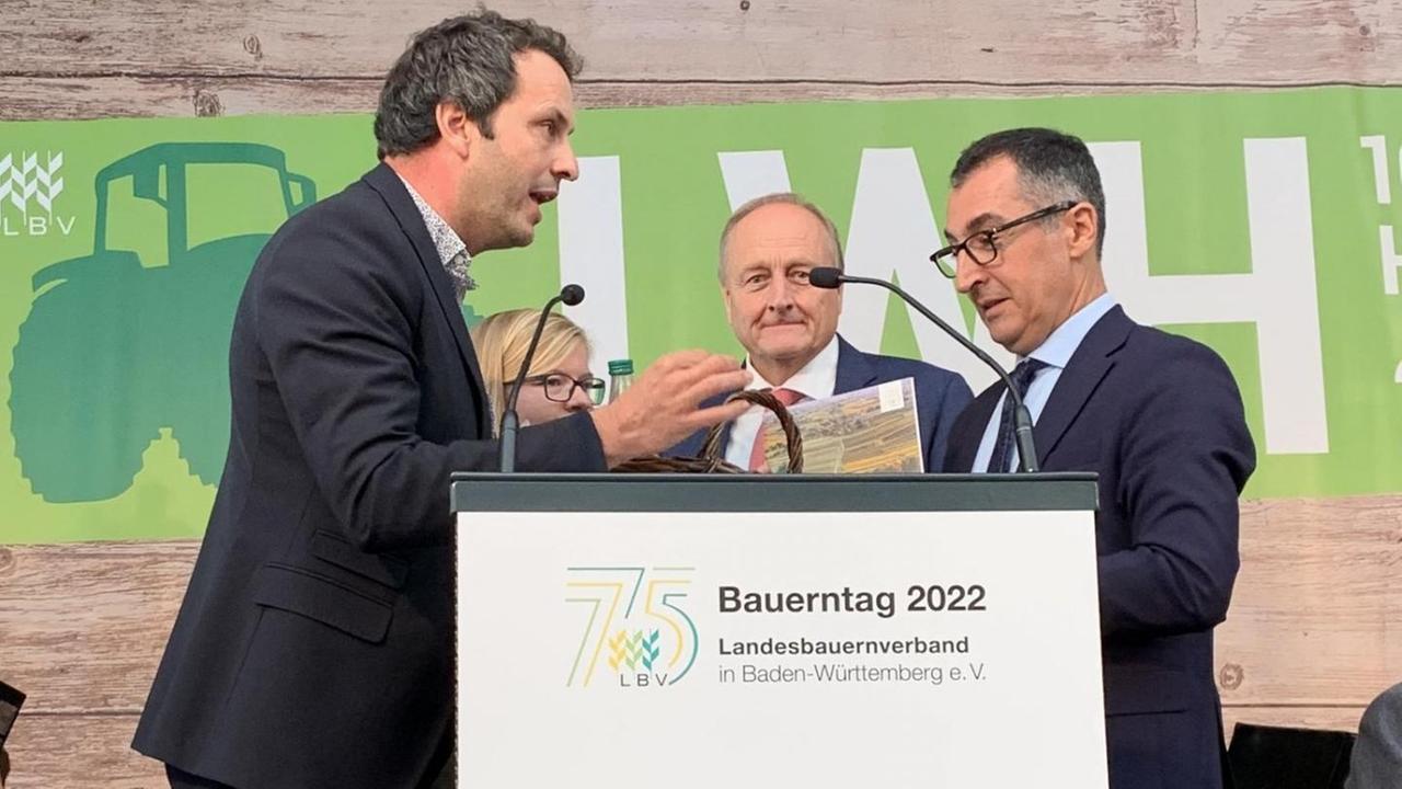 Links vom Rednerpult auf dem Bauerntag in Stuttgart steht Bauer Stefan Kerner, rechts steht Landwirtschaftsminister Cem Özdemir.