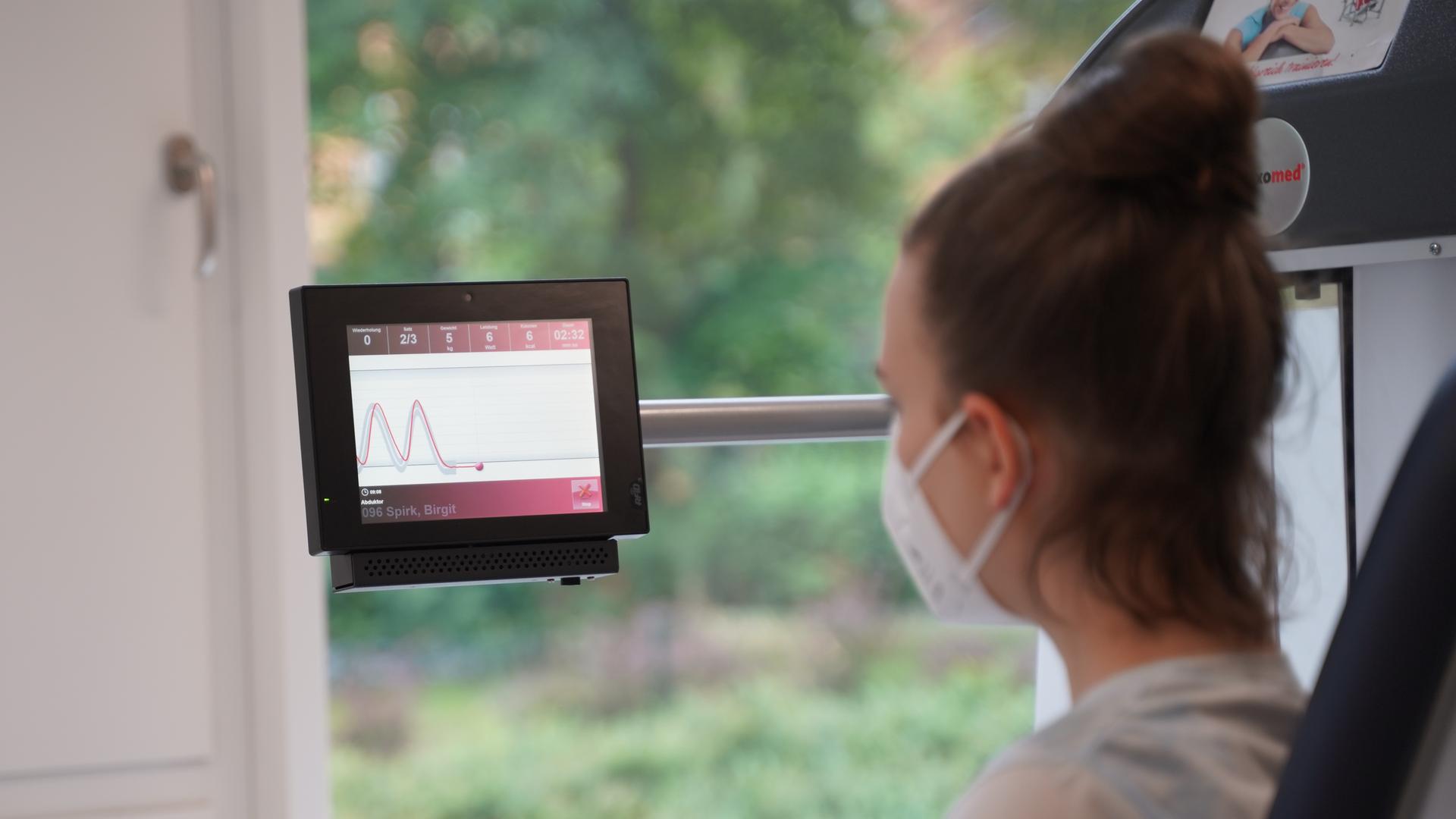 Eine "Long Covid"-Patientin sitzt auf einem Stuhl und schaut auf einen Monitor Eine "Long Covid"-Patientin sitzt auf einem Stuhl und schaut auf einen Monitor