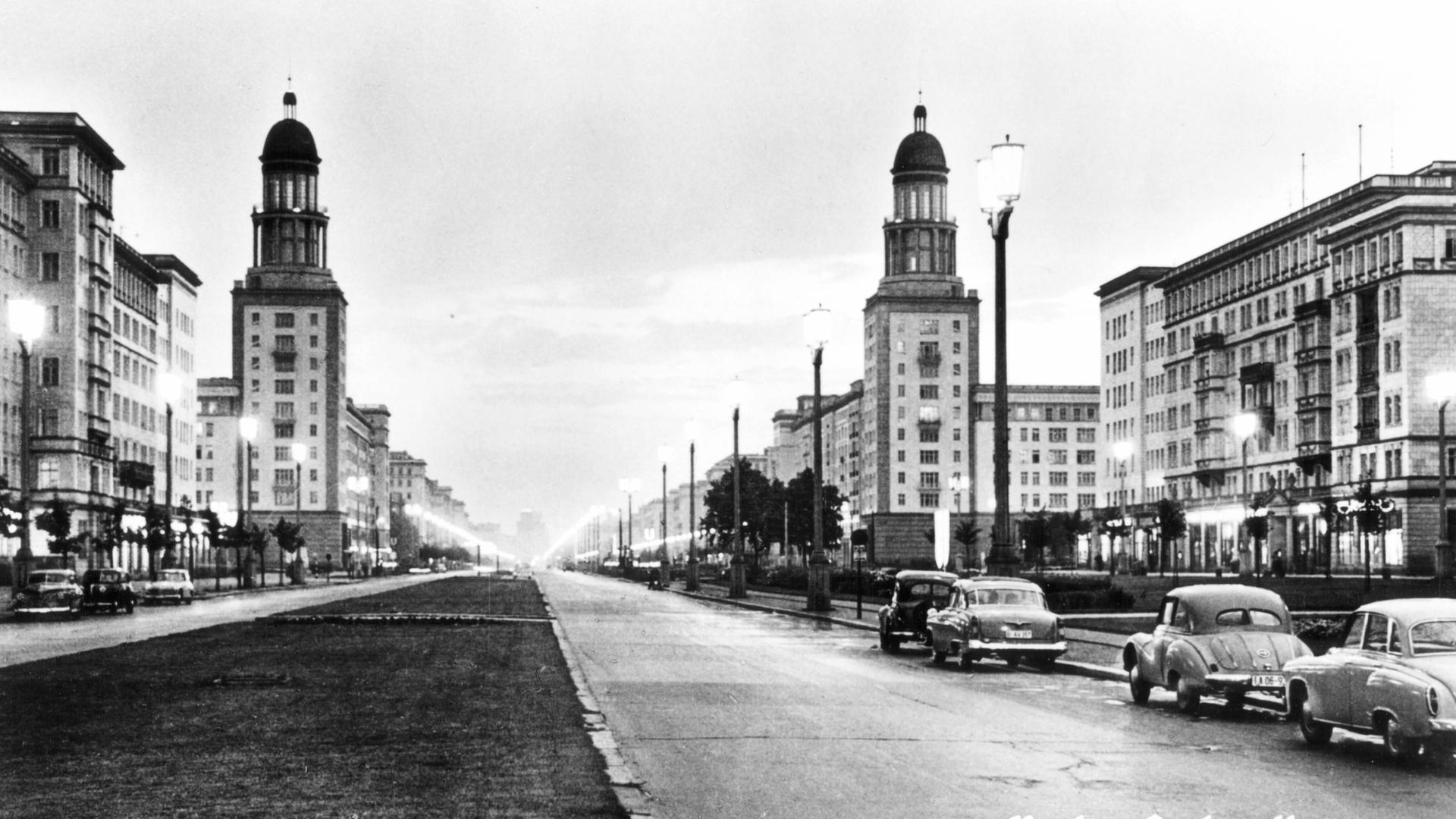Schwarzweißaufnahme der Stalinallee: Der breite Boulevard ist von Kächelgebäuden im klassizistischen Stil gesäumt. Schwarzweißaufnahme der Stalinallee: Der breite Boulevard ist von Kächelgebäuden im klassizistischen Stil gesäumt.