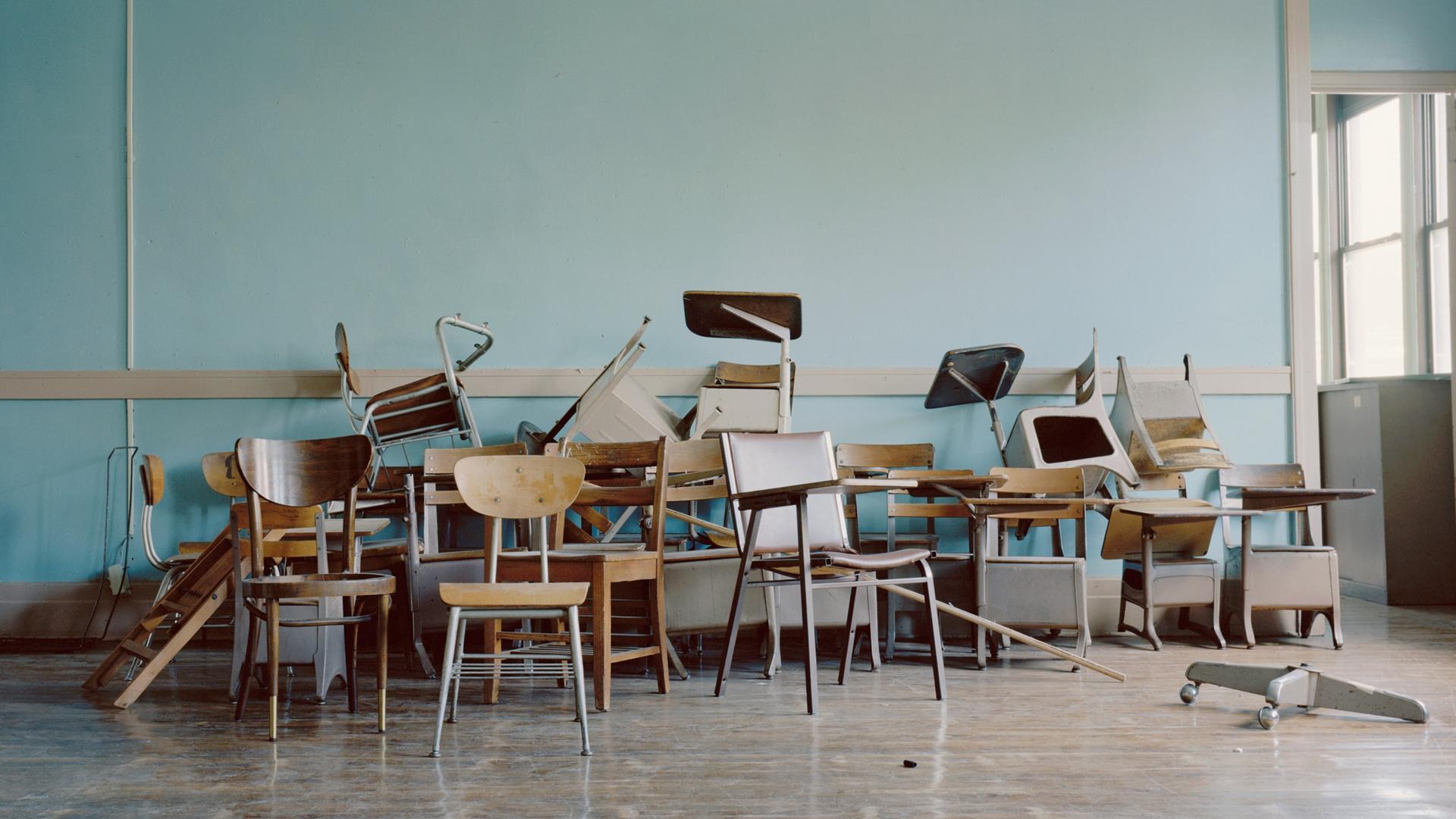 Alte Stühle liegen in einem leeren Klassenraum herum. Alte Stühle liegen in einem leeren Klassenraum herum.