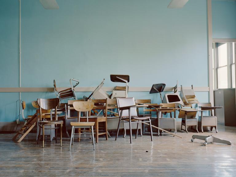 Alte Stühle liegen in einem leeren Klassenraum herum.