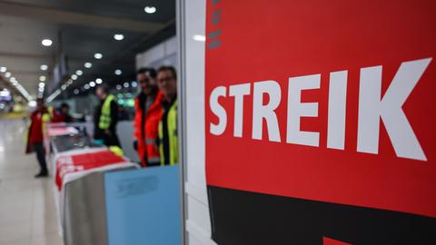 Das Foto zeigt Streikende am Flughafen Köln/Bonn. Sie tragen Warnwesten und stehen neben einem Schild mit der Aufschrift "Streik".