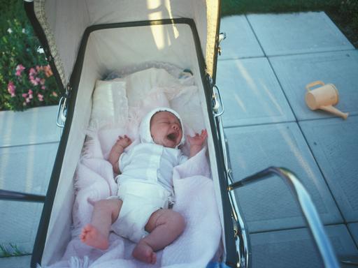 Ein neugeborenes Baby weint im einem Kinderwagen. Ein Foto aus einem privaten Familienalbum.