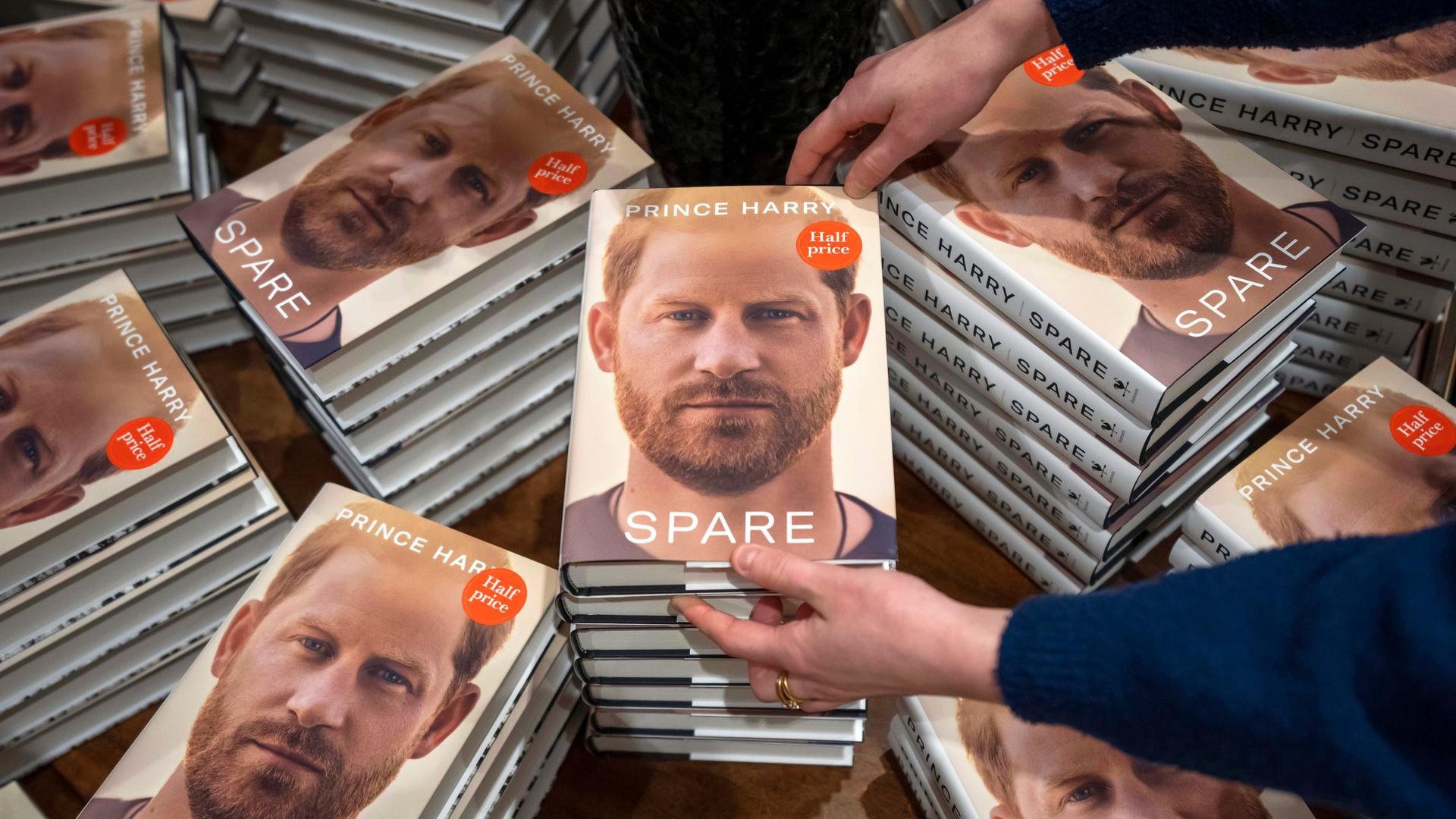 Ein Mitarbeiter einer Buchhandlung platziert die Exemplare der neu erschienenen Autobiografie von Prinz Harry mit dem Titel "Spare" ("Reserve") auf einem Tisch. Ein Mitarbeiter einer Buchhandlung platziert die Exemplare der neu erschienenen Autobiografie von Prinz Harry mit dem Titel "Spare" ("Reserve") auf einem Tisch.