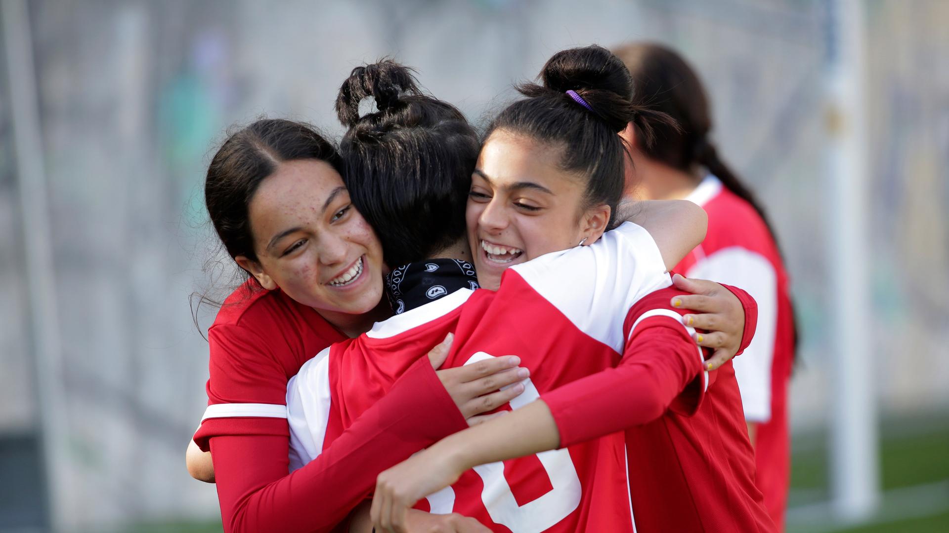 Members of the Afghanistan national girls soccer teams hug during a training session at a soccer pitch in Odivelas, outside Lisbon, Thursday, Sept. 30, 2021. The girls and their families arrived in Portugal Sept.19 after an international coalition came to their rescue. (AP Photo/Ana Brigida)