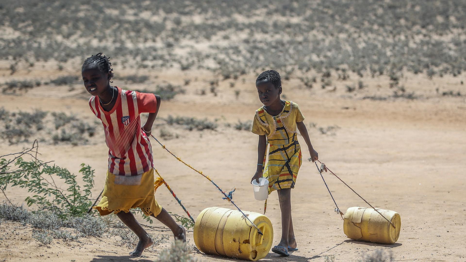 Dürre in Kenia im Mai 2022: Junge Mädchen ziehen Wasserbehälter, nachdem sie von einem Brunnen im Dorf Lomoputh im Norden Kenias zu ihren Hütten zurückkehren Dürre in Kenia im Mai 2022: Junge Mädchen ziehen Wasserbehälter, nachdem sie von einem Brunnen im Dorf Lomoputh im Norden Kenias zu ihren Hütten zurückkehren