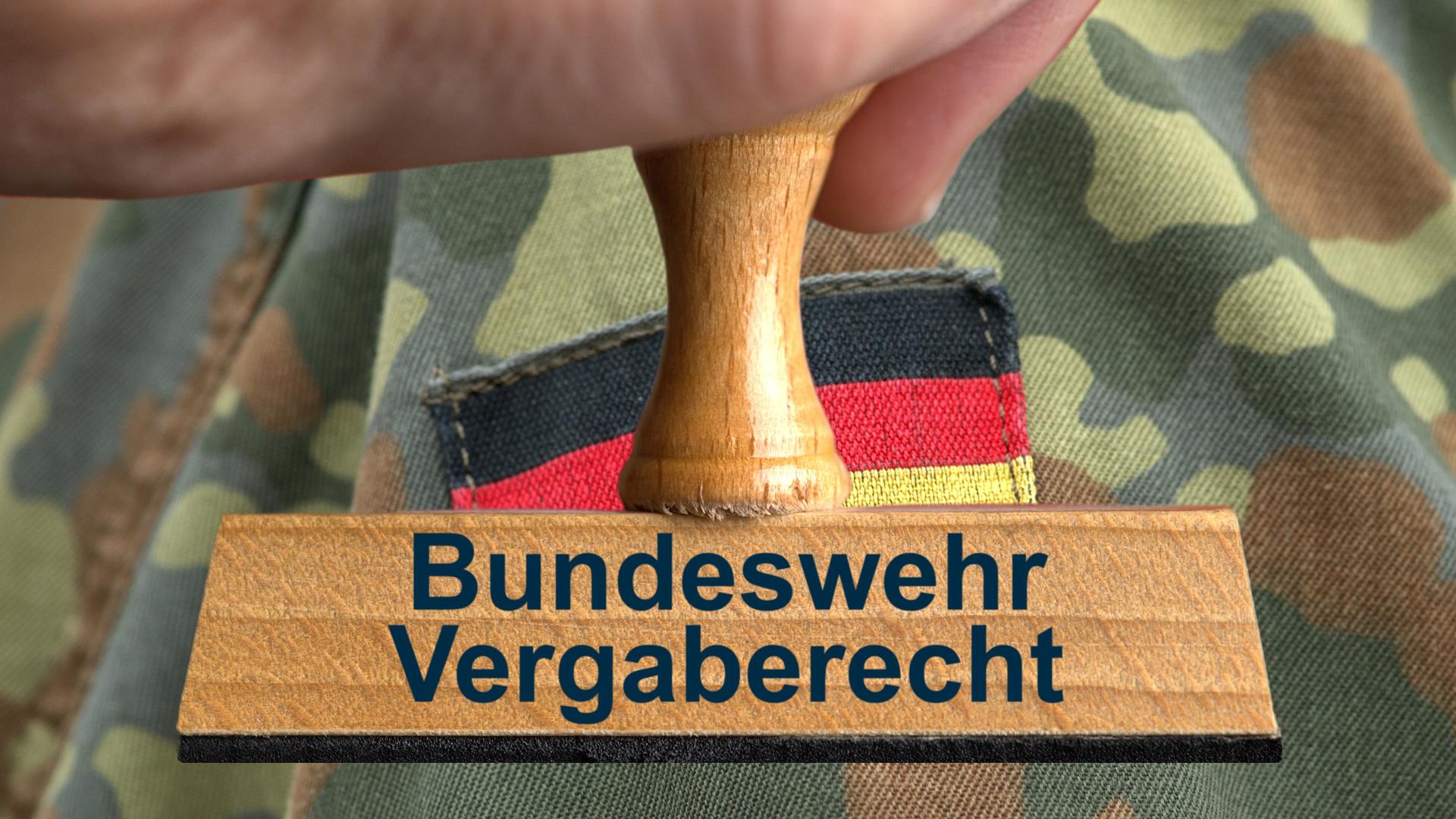 Ein symbolischer Holzstempel, gehalten von einer Hand mit der Aufschrift "Bundeswehr Vergaberecht" vor dem Ärmel eines Soldaten in Uniform mit Deutschlandflagge auf dem Ãrmel im Anschnitt.