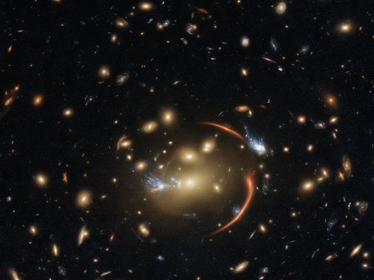 Die „Macht“, die Dunkle Energie, beeinflusst sicher auch den Galaxienhaufen MACSJ0138.0-2155 und die weit dahinter liegenden Galaxien