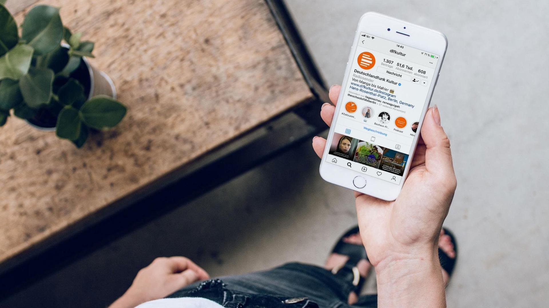 Eine junge Frau hält ein weißes Smartphone auf dessen Display das Instagram Profil von Deutschlandfunk Kultur zu sehen ist. Eine junge Frau hält ein weißes Smartphone auf dessen Display das Instagram Profil von Deutschlandfunk Kultur zu sehen ist.