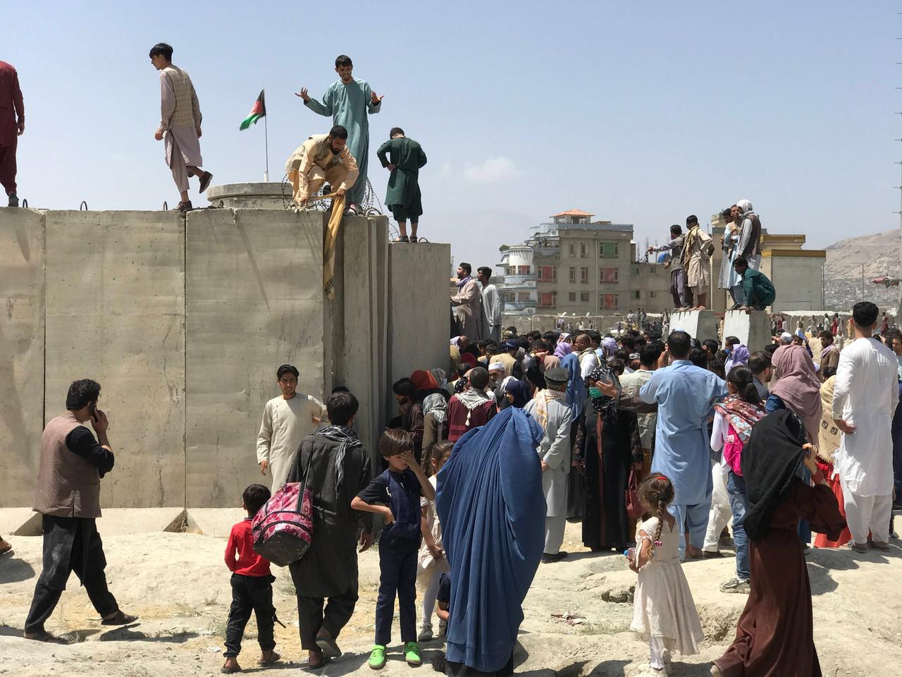 Menschen erklimmen die Mauer um den Kabuler Flughafen. Menschen erklimmen die Mauer um den Kabuler Flughafen.