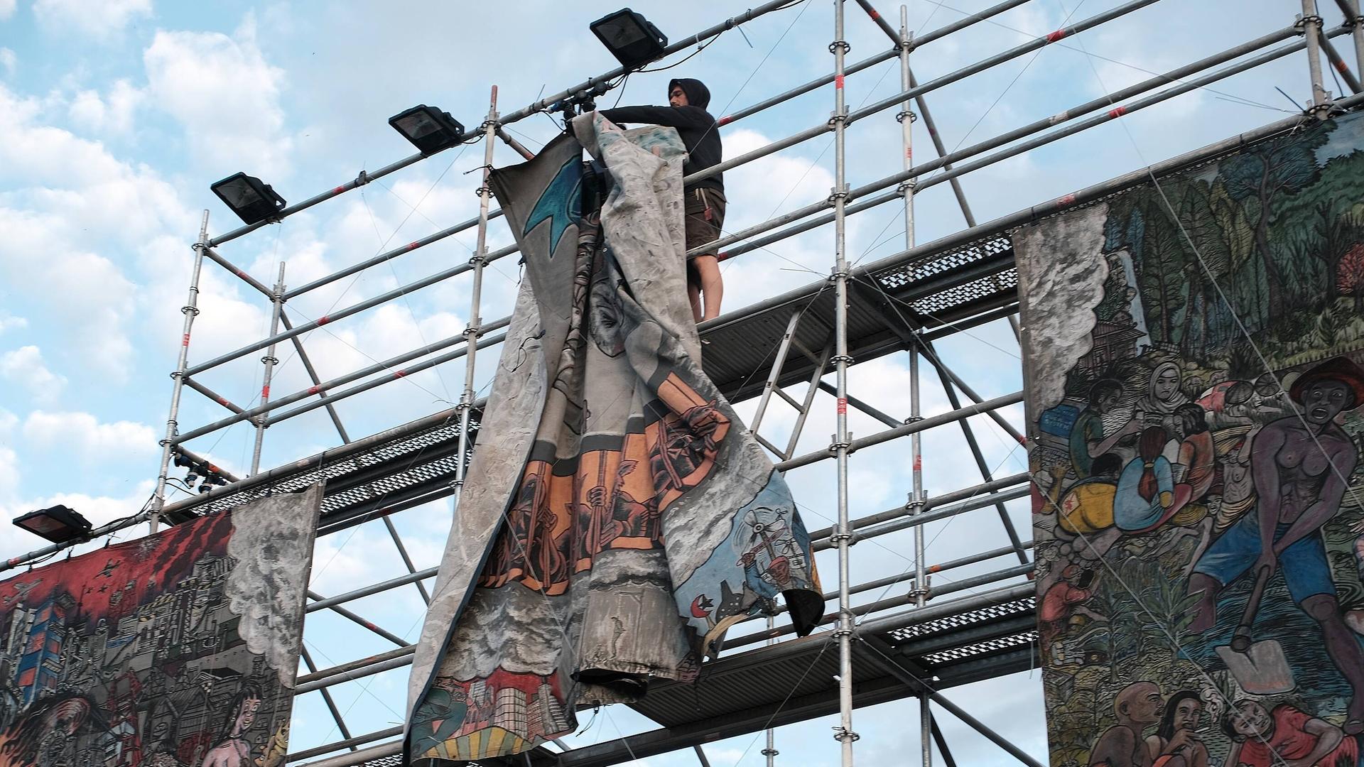 Das Gemälde des indonesischen Künstlerkollektivs Taring Padi auf der Documenta mit eindeutig antisemitischen Darstellungen wird abgehängt - am Schluss steht nur noch das leere Gerüst . Das Gemälde des indonesischen Künstlerkollektivs Taring Padi auf der Documenta mit eindeutig antisemitischen Darstellungen wird abgehängt - am Schluss steht nur noch das leere Gerüst .