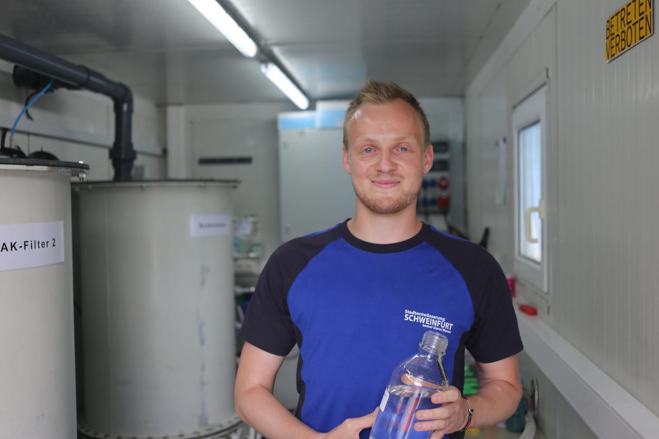 Markus Büttner steht mit einer Wasserflasche in der Hand auf dem Gelände der Kläranlage Schweinfurt und schaut in die Kamera. Markus Büttner steht mit einer Wasserflasche in der Hand auf dem Gelände der Kläranlage Schweinfurt und schaut in die Kamera.