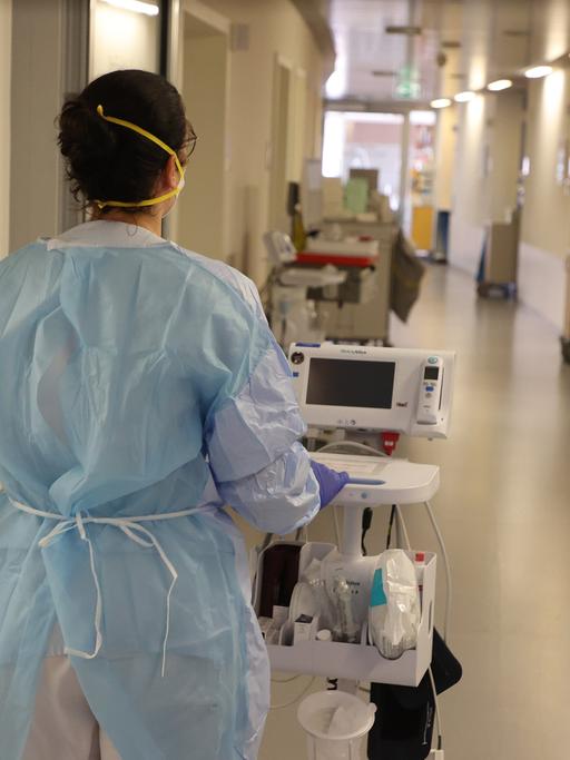 Eine Krankenschwester läuft mit medizinischem Gerät auf einer Coronastation