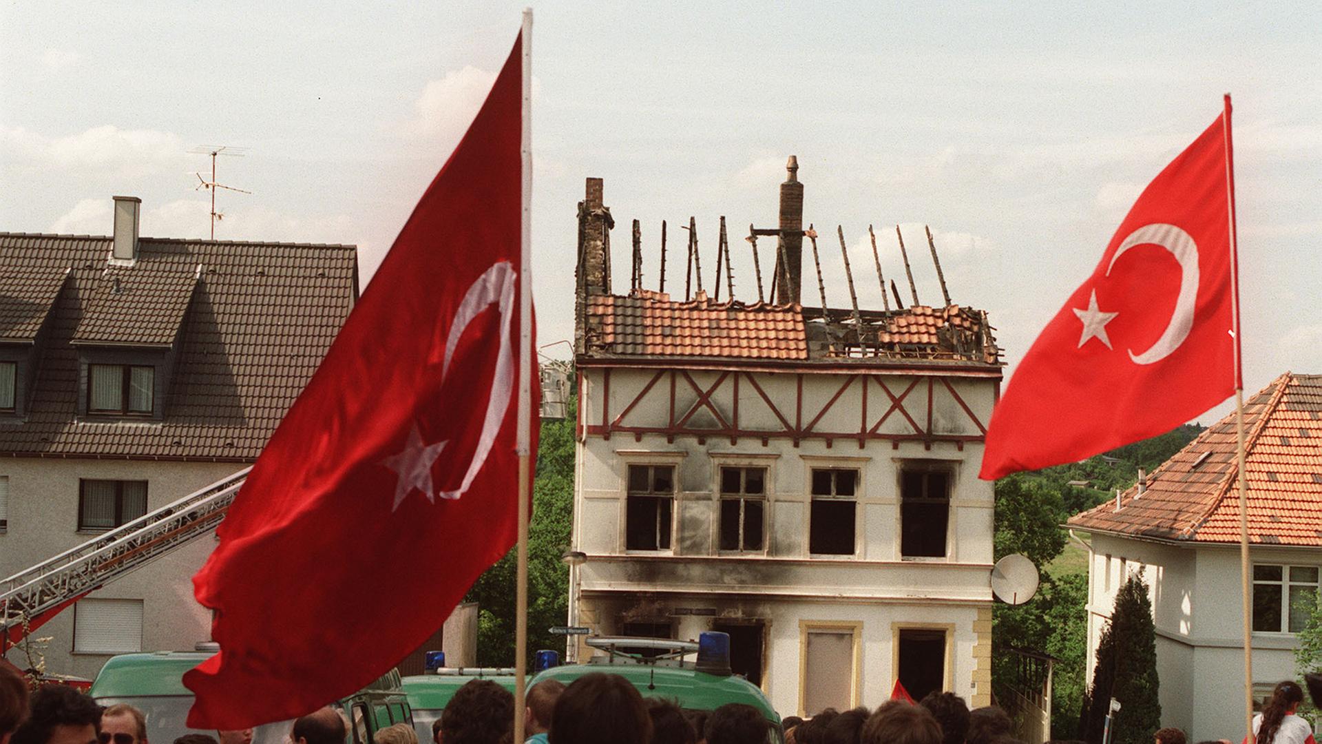 Demonstranten tragen am 29. Mai 1993 vor dem ausgebrannten Haus der Familie Genç in Solingen türkische Fahnen. Demonstranten tragen am 29. Mai 1993 vor dem ausgebrannten Haus der Familie Genç in Solingen türkische Fahnen.