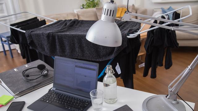  Eine Arbeitsecke mit Laptop, Buerolampe und Ordnern wurde in einem Wohnzimmer eingerichtet, aufgenommen am 13.02.2021 in Wittenberge. Im Hintergrund ist ein behangener Waeschestaender 