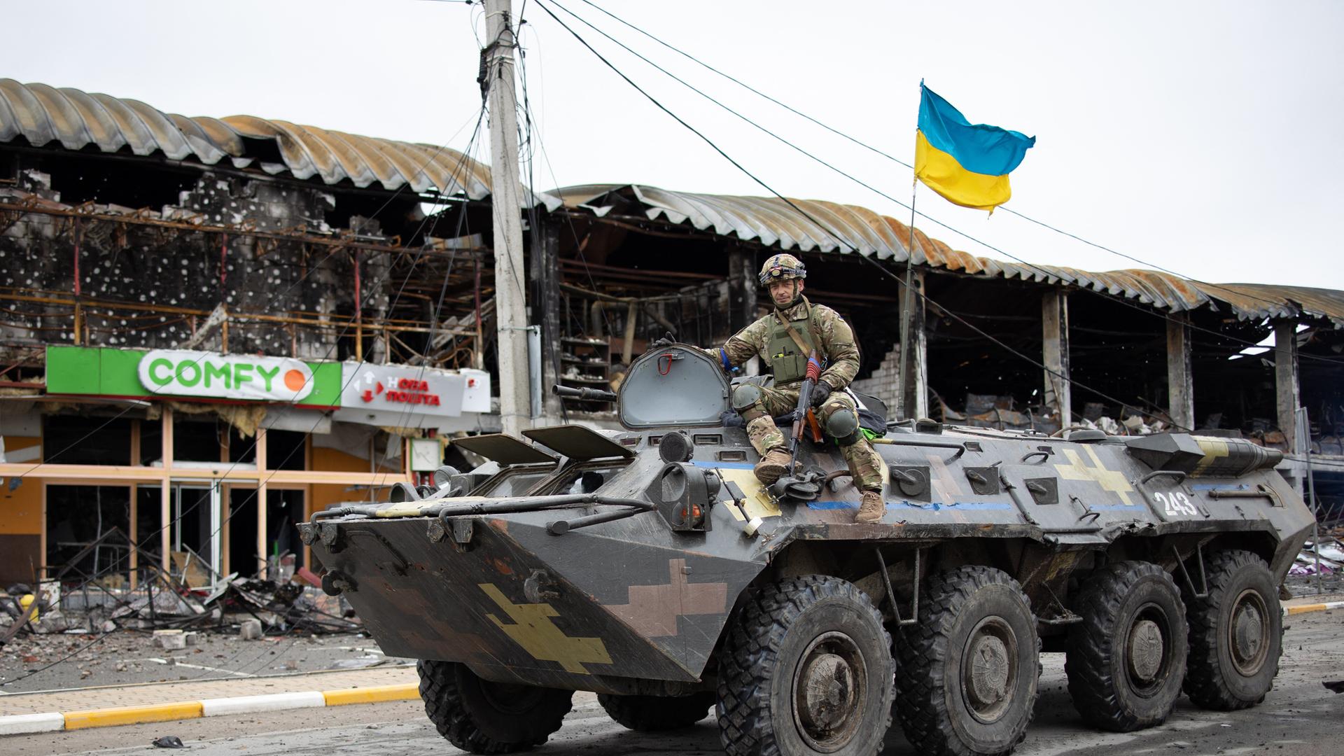Ukrainischer Soldat auf einem Panzer in einer kriegszerstörten Straße in Irpin