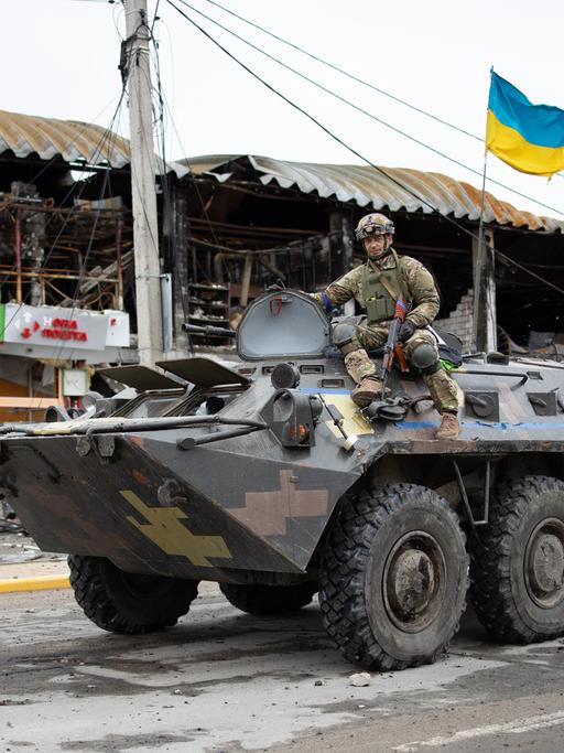 Ukrainischer Soldat auf einem Panzer in einer kriegszerstörten Straße in Irpin