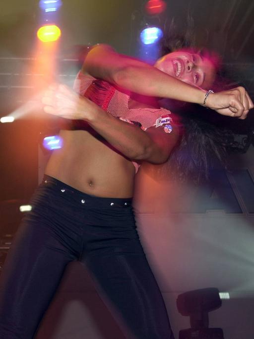 Eine Frau tanzt in einem Nachtclub, umgeben von farbigen Lichtern.