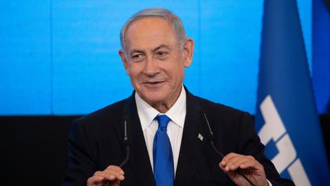 Der Vorsitzende der Likud-Partei und ehemalige israelische Ministerpräsident Benjamin Netanjahu steht lächelnd vor einem Mikrofon. 