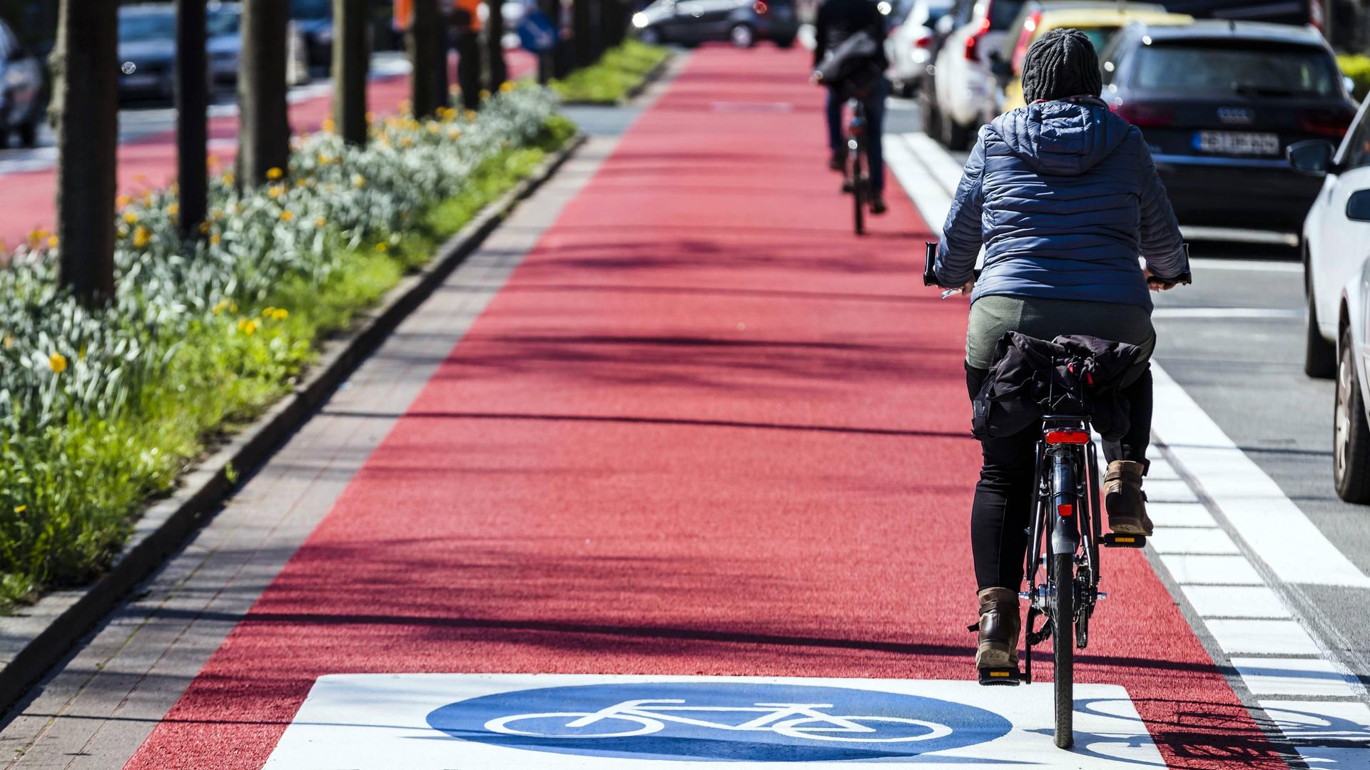 Menschen fahren auf einer roten Fahrradstraße mit ihrem Fahrrad. Menschen fahren auf einer roten Fahrradstraße mit ihrem Fahrrad.