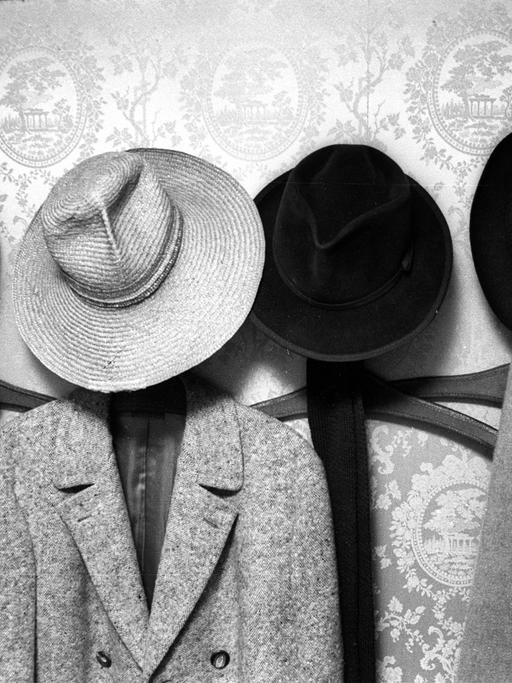 Garderobe mit diversen Hüten an Haken.