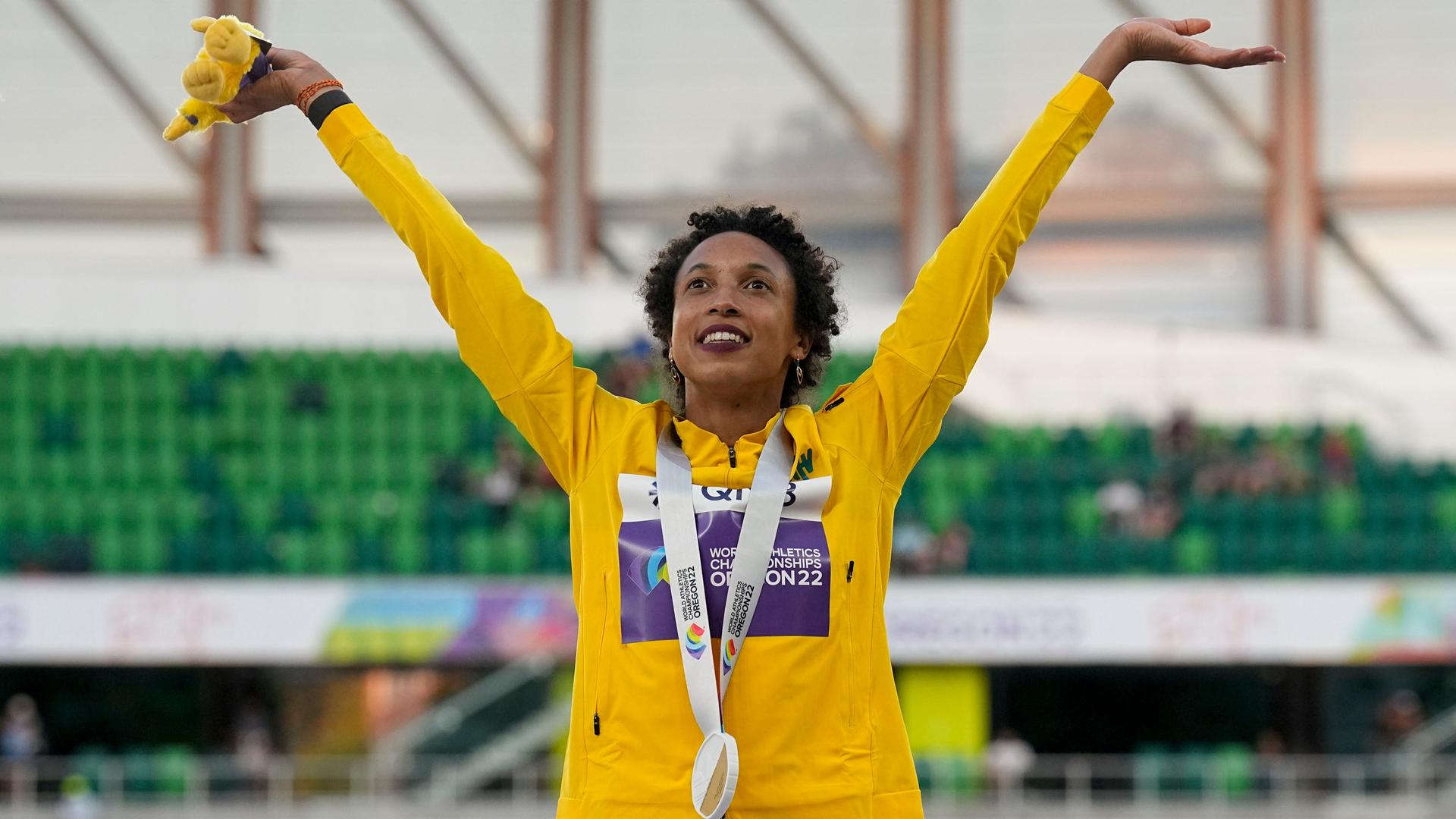 Die Weitspringerin Malaika Mihambo steht im Stadion in Oregon und reckt beide Arme in die Höhe. Um den Hals trägt sie ihre Goldmedaille. Die Weitspringerin Malaika Mihambo steht im Stadion in Oregon und reckt beide Arme in die Höhe. Um den Hals trägt sie ihre Goldmedaille.