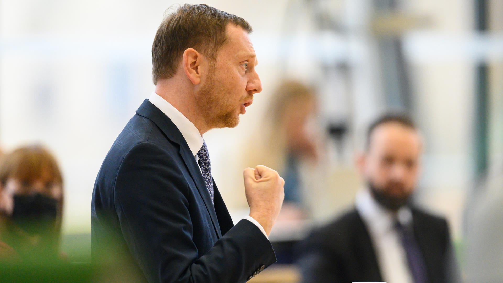 Ministerpräsident Kretschmer spricht am Rednerpult im Landtag. Er hat den Arm angewinkelt und die geballte Faust vor dem Oberkörper. Ministerpräsident Kretschmer spricht am Rednerpult im Landtag. Er hat den Arm angewinkelt und die geballte Faust vor dem Oberkörper.