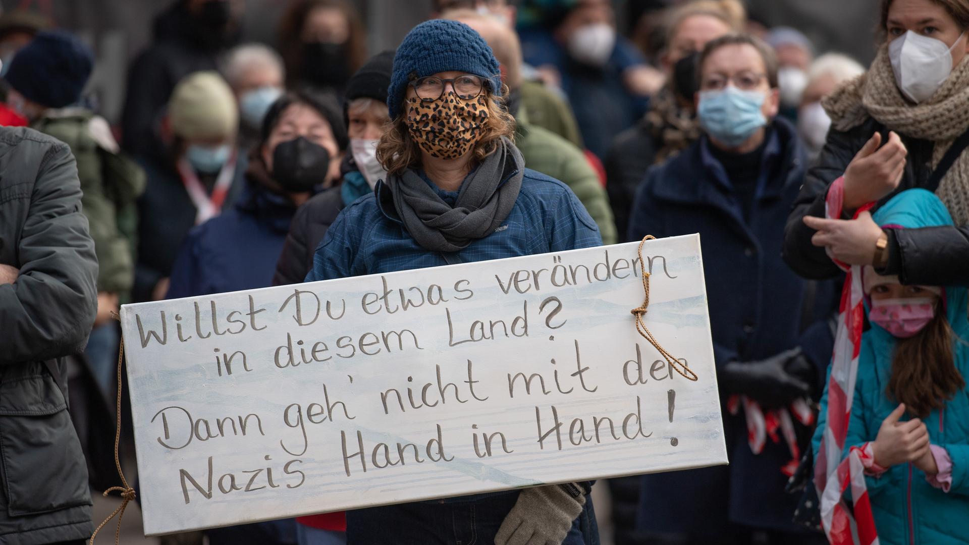 Teilnehmende einer Demonstration gegen Querdenker. Eine Frau hält ein Anti-Nazi-Schild hoch. Teilnehmende einer Demonstration gegen Querdenker. Eine Frau hält ein Anti-Nazi-Schild hoch.