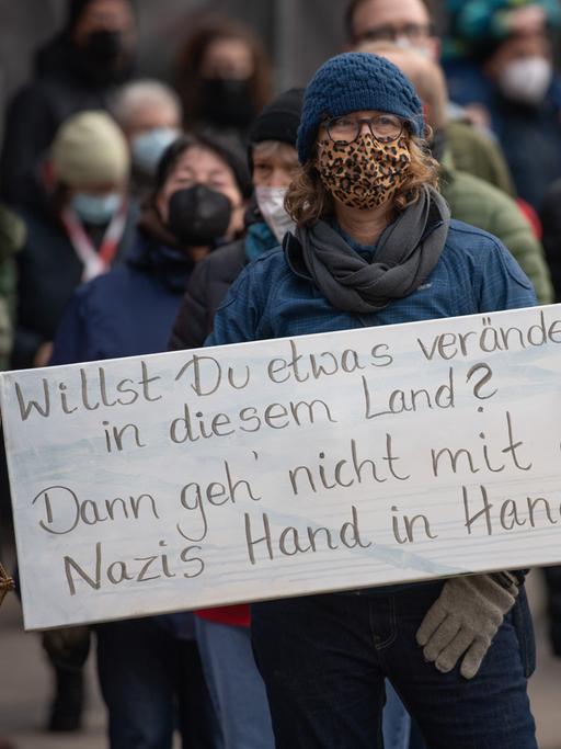 Teilnehmende einer Demonstration gegen Querdenker. Eine Frau hält ein Anti-Nazi-Schild hoch.