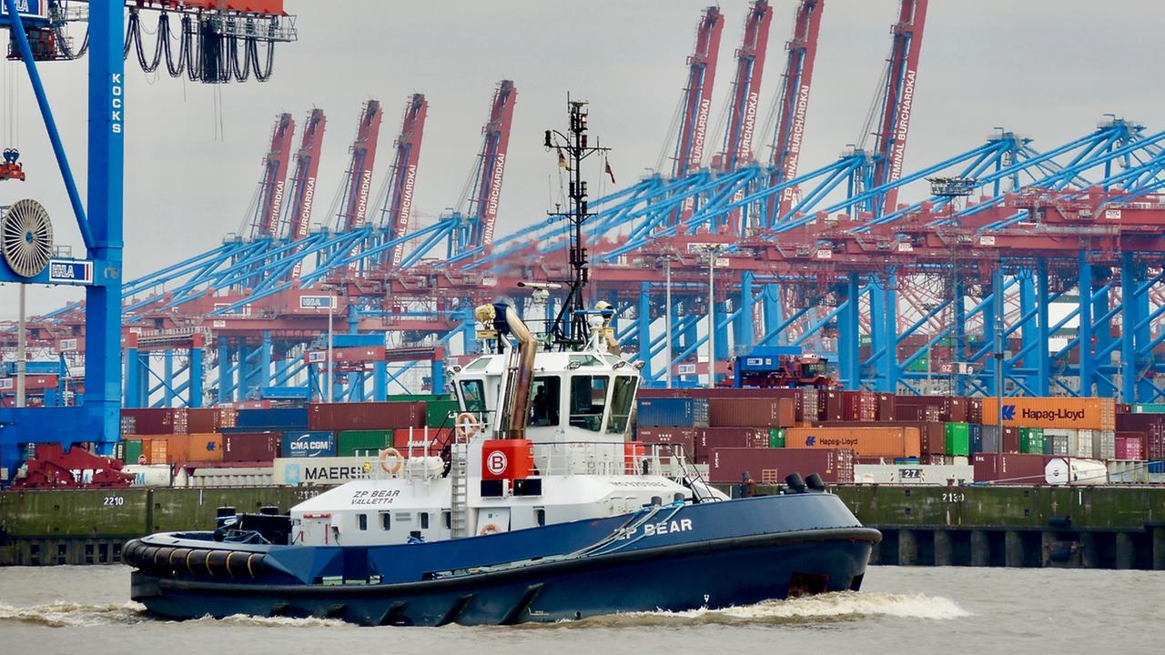 Ein Schlepper vor der Kulisse des Containerterminals Burchardkai im Hamburger Hafen, im Hintergrund die riesigen Portalbrücken- Kräne