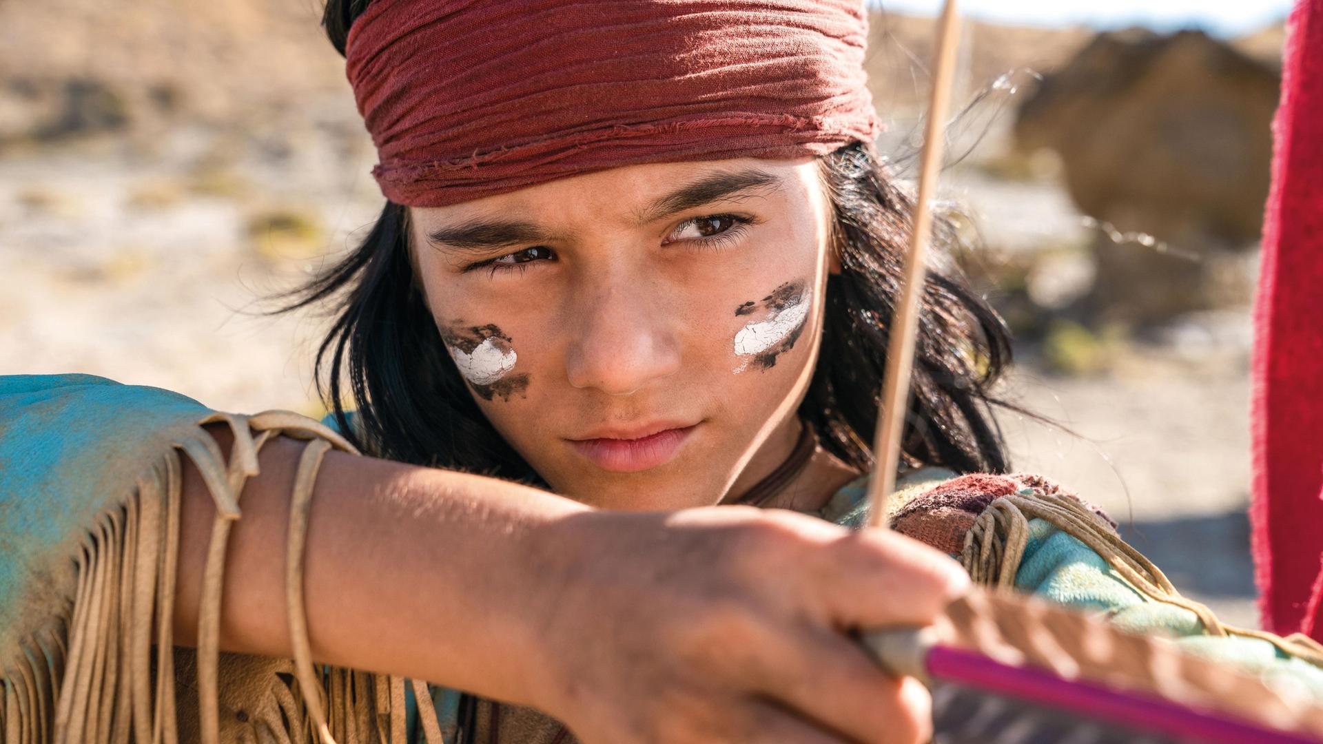 Ein Junge in einem Winnetou-Kostüm schießt mit Pfeil und Bogen. Ein Junge in einem Winnetou-Kostüm schießt mit Pfeil und Bogen.