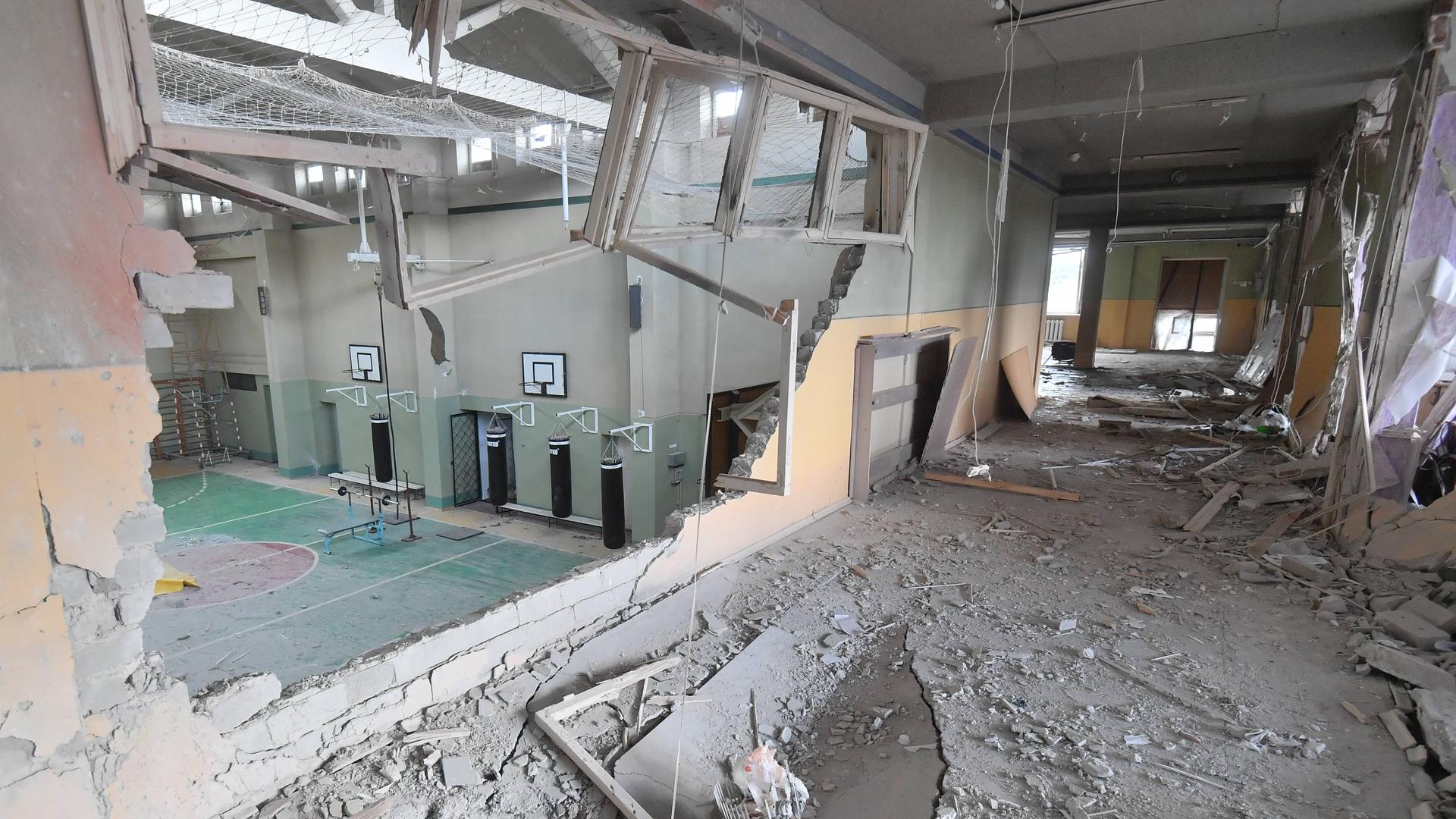 Durch ein Loch in der Wand ist die zerstörte Turnhalle einer Schule zu sehen. Durch ein Loch in der Wand ist die zerstörte Turnhalle einer Schule zu sehen.