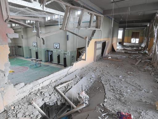 Durch ein Loch in der Wand ist die zerstörte Turnhalle einer Schule zu sehen.
