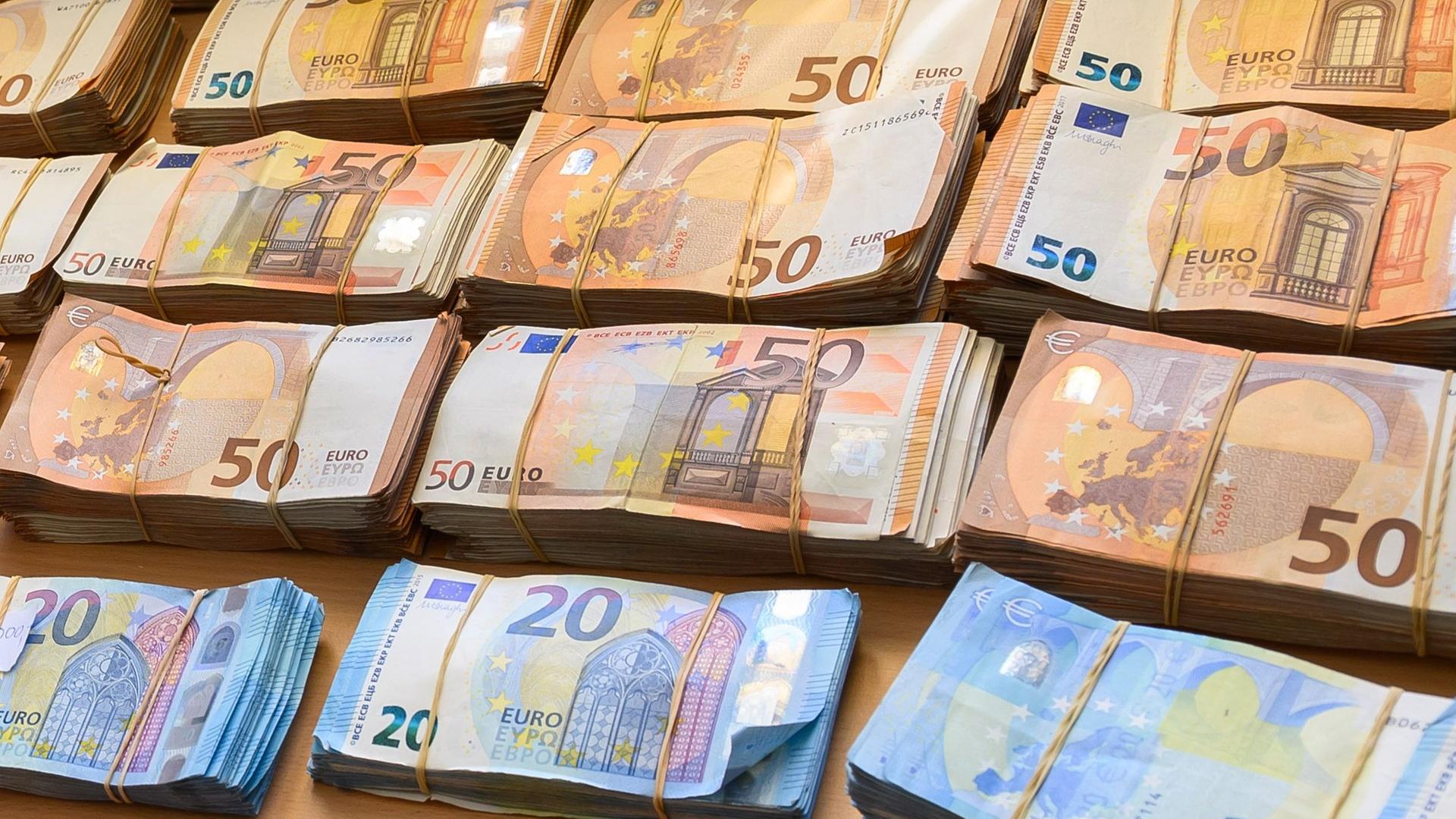 Das Foto zeigt mehrere Bündel mit Euro-Banknoten auf einem Tisch. Das Foto zeigt mehrere Bündel mit Euro-Banknoten auf einem Tisch.