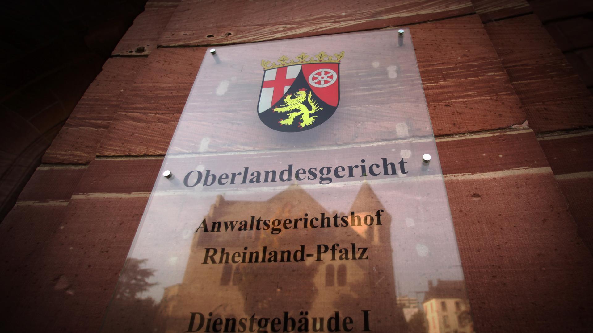 Im Türschild des Oberlandesgerichts spiegelt sich am 19.10.2012 in Koblenz ein weiteres Verwaltungsgebäude der Rechtsbehörde. Foto: Fredrik von Erichsen/dpa