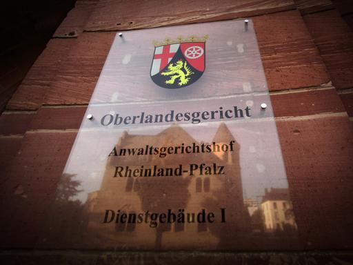 Im Türschild des Oberlandesgerichts spiegelt sich am 19.10.2012 in Koblenz ein weiteres Verwaltungsgebäude der Rechtsbehörde. Foto: Fredrik von Erichsen/dpa