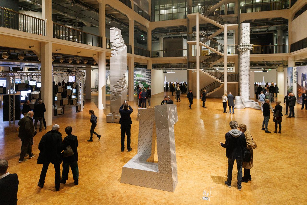 Ausstellungsbesucher betrachten Architekturmodelle der Bauten von Ole Scheeren. Ausstellungsbesucher betrachten Architekturmodelle der Bauten von Ole Scheeren.