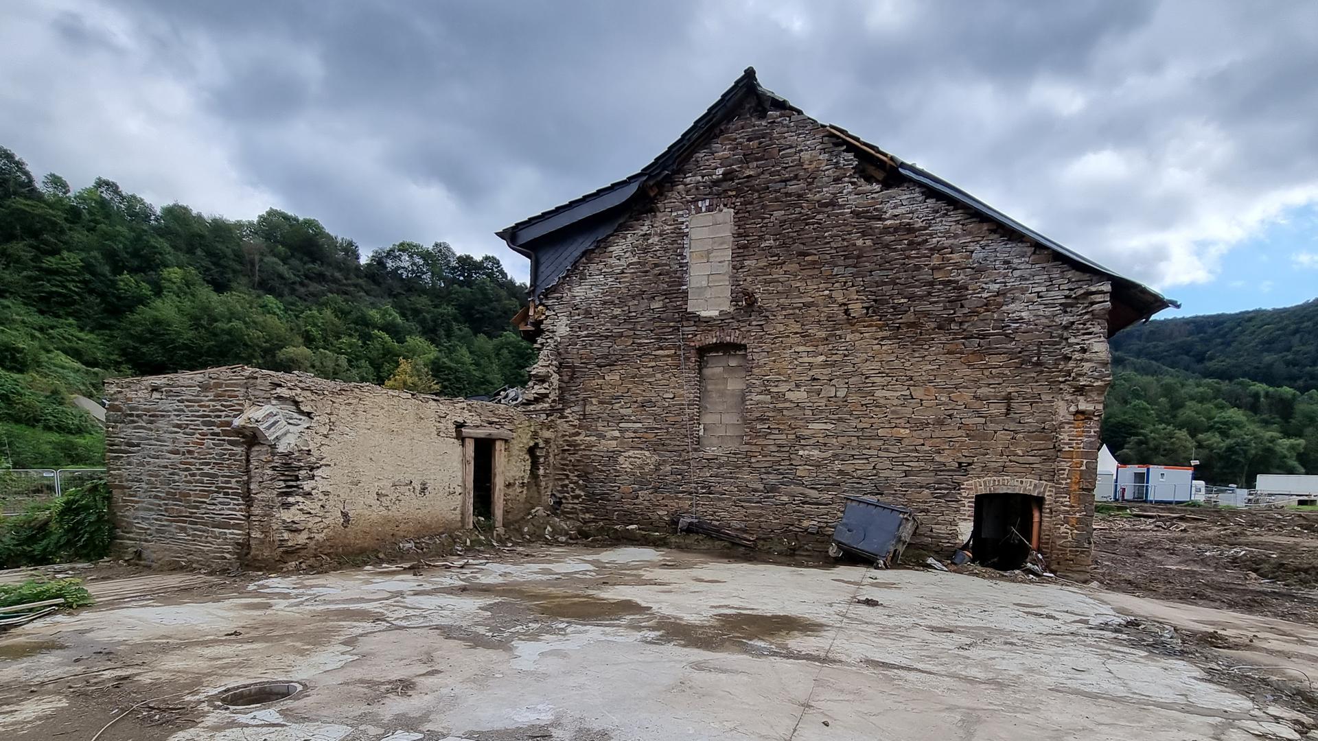 Vor dramatischem Himmel erhebt sich ein zerfallenes Backsteinhaus umgeben von einer Brachfläche. Vor dramatischem Himmel erhebt sich ein zerfallenes Backsteinhaus umgeben von einer Brachfläche.