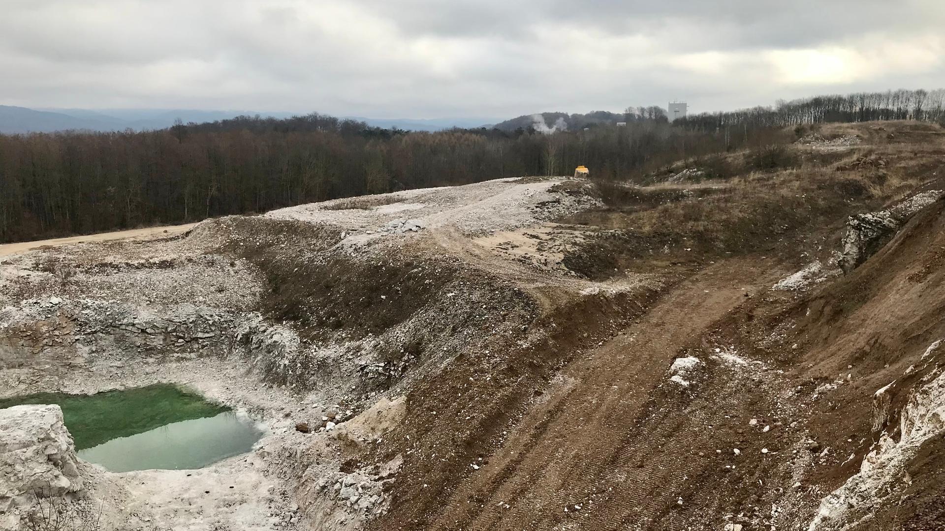In einem Gipssteinbruch sind unten links kleine Seen zu sehen, je weiter nach rechts das Auge blickt, um so höher reicht das Erdreich. Weiter links haben Bagger Gips abgebaut, es ist Erdreich zu sehen. Im Hintergrund ist eine winterliche Waldlandschaft zu erkennen. In einem Gipssteinbruch sind unten links kleine Seen zu sehen, je weiter nach rechts das Auge blickt, um so höher reicht das Erdreich. Weiter links haben Bagger Gips abgebaut, es ist Erdreich zu sehen. Im Hintergrund ist eine winterliche Waldlandschaft zu erkennen.