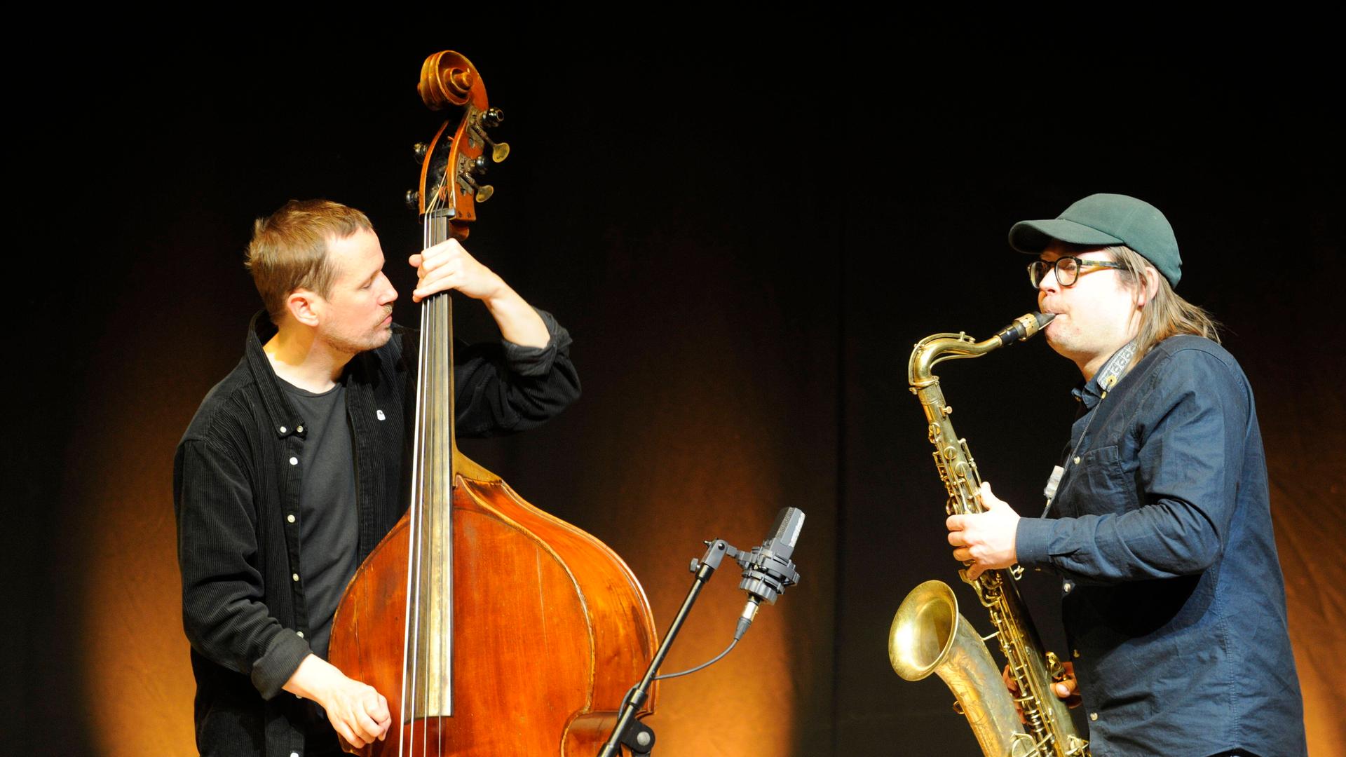 Der Bassist Petter Eldh und der Saxofonist Otis Sandsjö stehen sich mit ihren Instrumenten sspielend gegenüber. Der Bassist Petter Eldh und der Saxofonist Otis Sandsjö stehen sich mit ihren Instrumenten sspielend gegenüber.