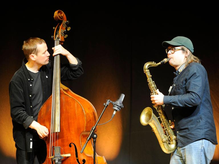 Der Bassist Petter Eldh und der Saxofonist Otis Sandsjö stehen sich mit ihren Instrumenten sspielend gegenüber.