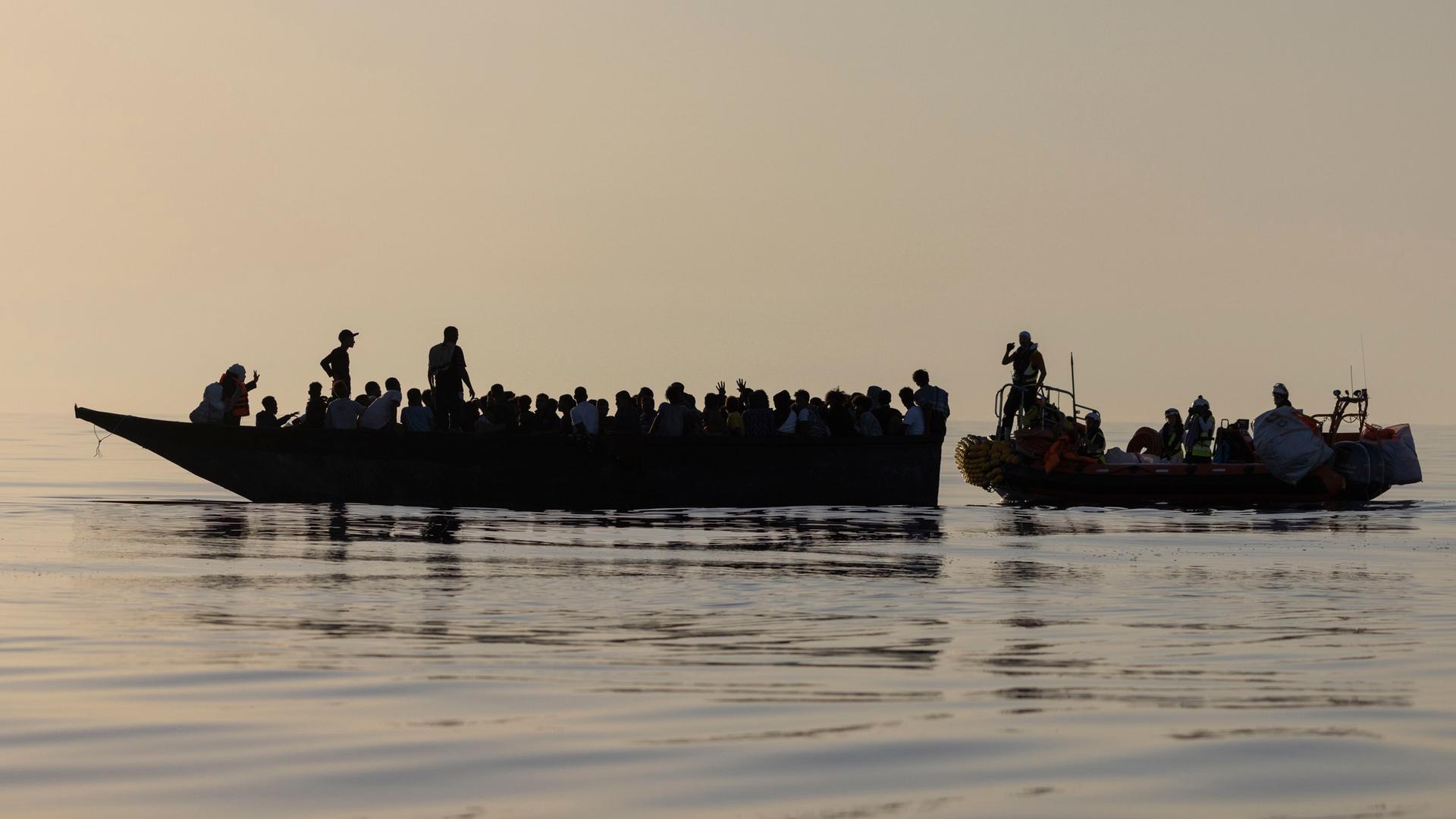 Migranten in einem Boot werden von Besatzungsmitgliedern der Ocean Viking gerettet.