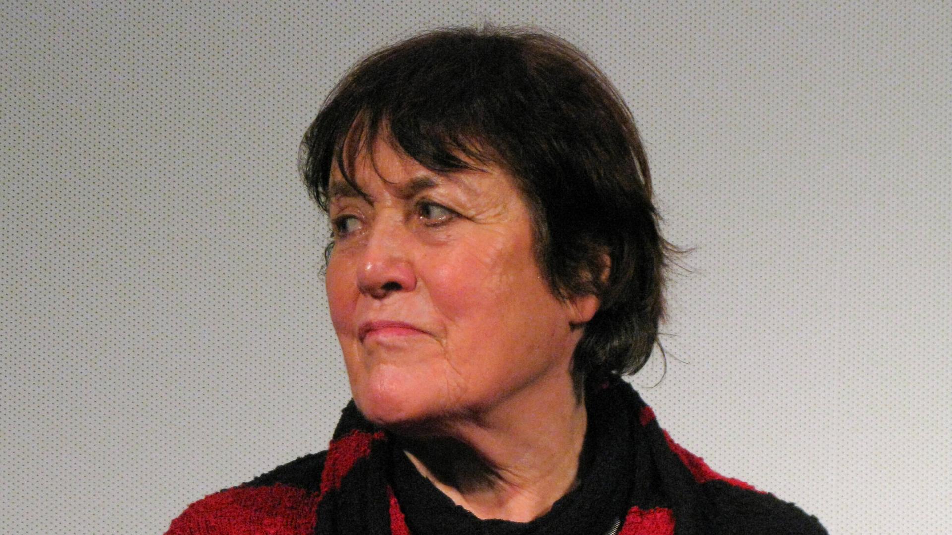 Die Dokumentarfilmerin Helga Reidemeister trägt einen schwarz-roten Pulli und Schal. Sie blickt rechts an der Kamera vorbei. Die Dokumentarfilmerin Helga Reidemeister trägt einen schwarz-roten Pulli und Schal. Sie blickt rechts an der Kamera vorbei.