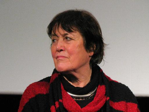 Die Dokumentarfilmerin Helga Reidemeister trägt einen schwarz-roten Pulli und Schal. Sie blickt rechts an der Kamera vorbei.
