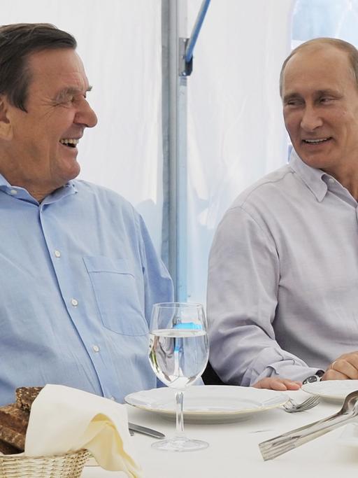 Russlands Präsident Wladimir Putin und der frühere Bundeskanzler Gerhard Schröder gemeinsam an einem gedeckten Tisch 2011 bei einem Treffen in Russland. 