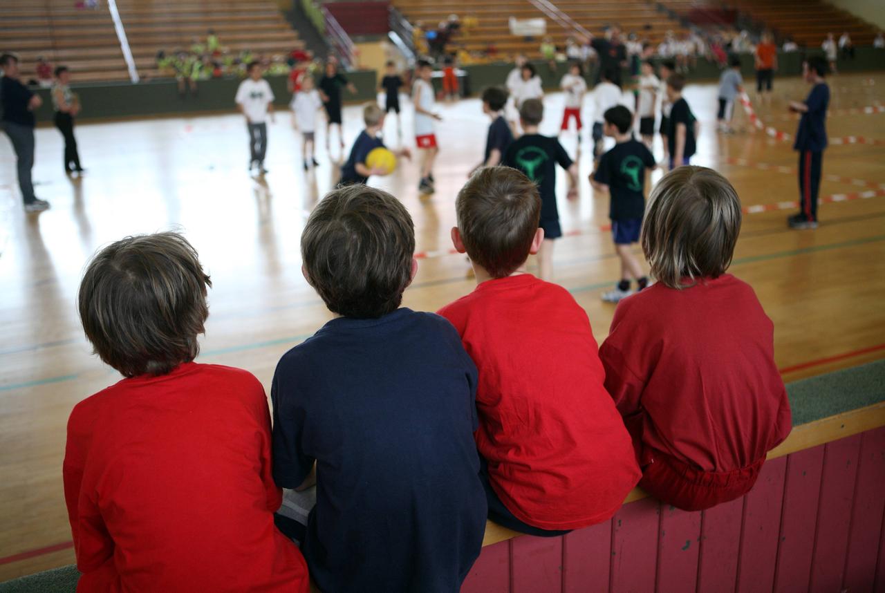 Kinder schauen beim Voelkerballspiel in einer Turnhalle zu.