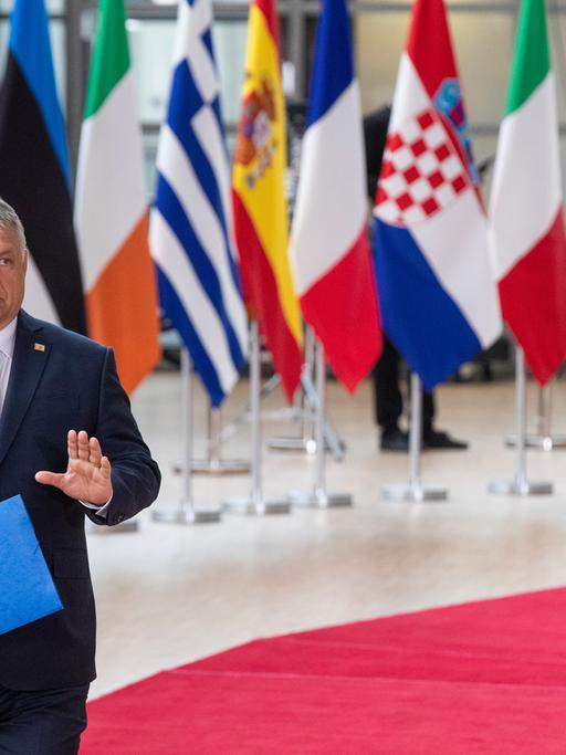 Ungarns Ministerpräsident Viktor Orbán läuft über einen roten Teppich in Brüssel und hebt die Hand