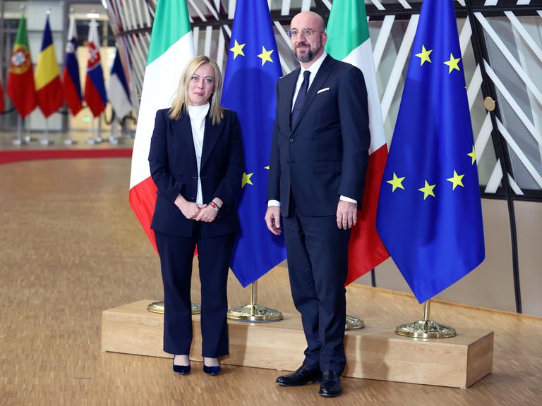 Italiens neue Regierungschefin Giorgia Meloni und der Präsident des Europäisches Rats Charles Michel stehen vor Flaggen Italiens und der EU. 