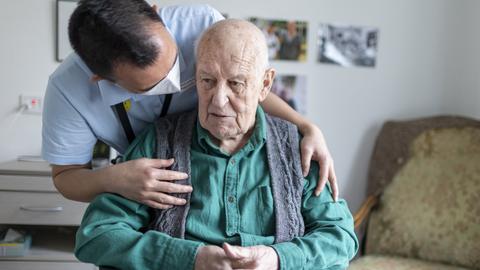 Altenpfleger redet mit einem Bewohner im Pflegeheim
